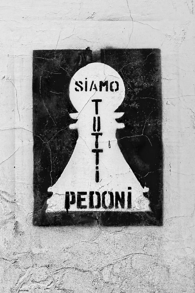 Black and white stencil reading Siamo tutti pedoni on a cracked wall